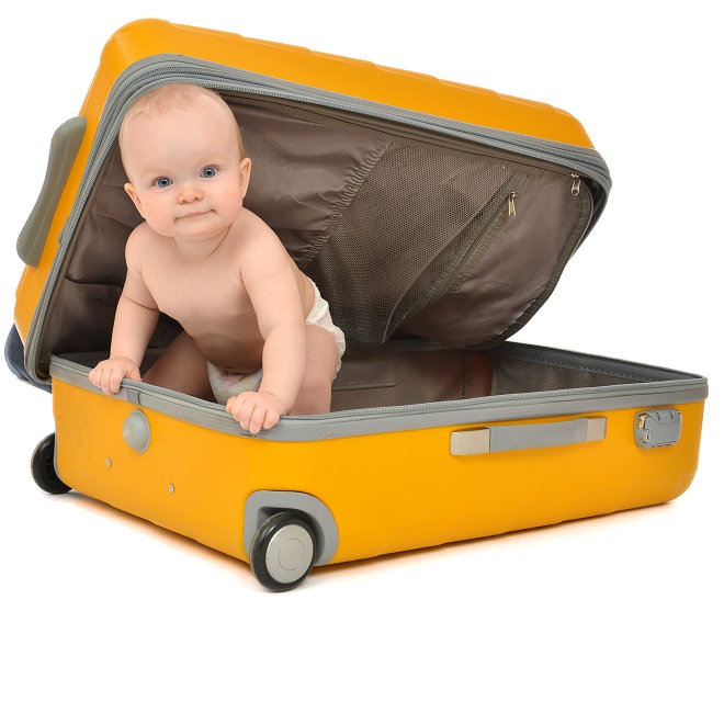 Happy infant baby toddler sitting in yellow plastic travel suitc